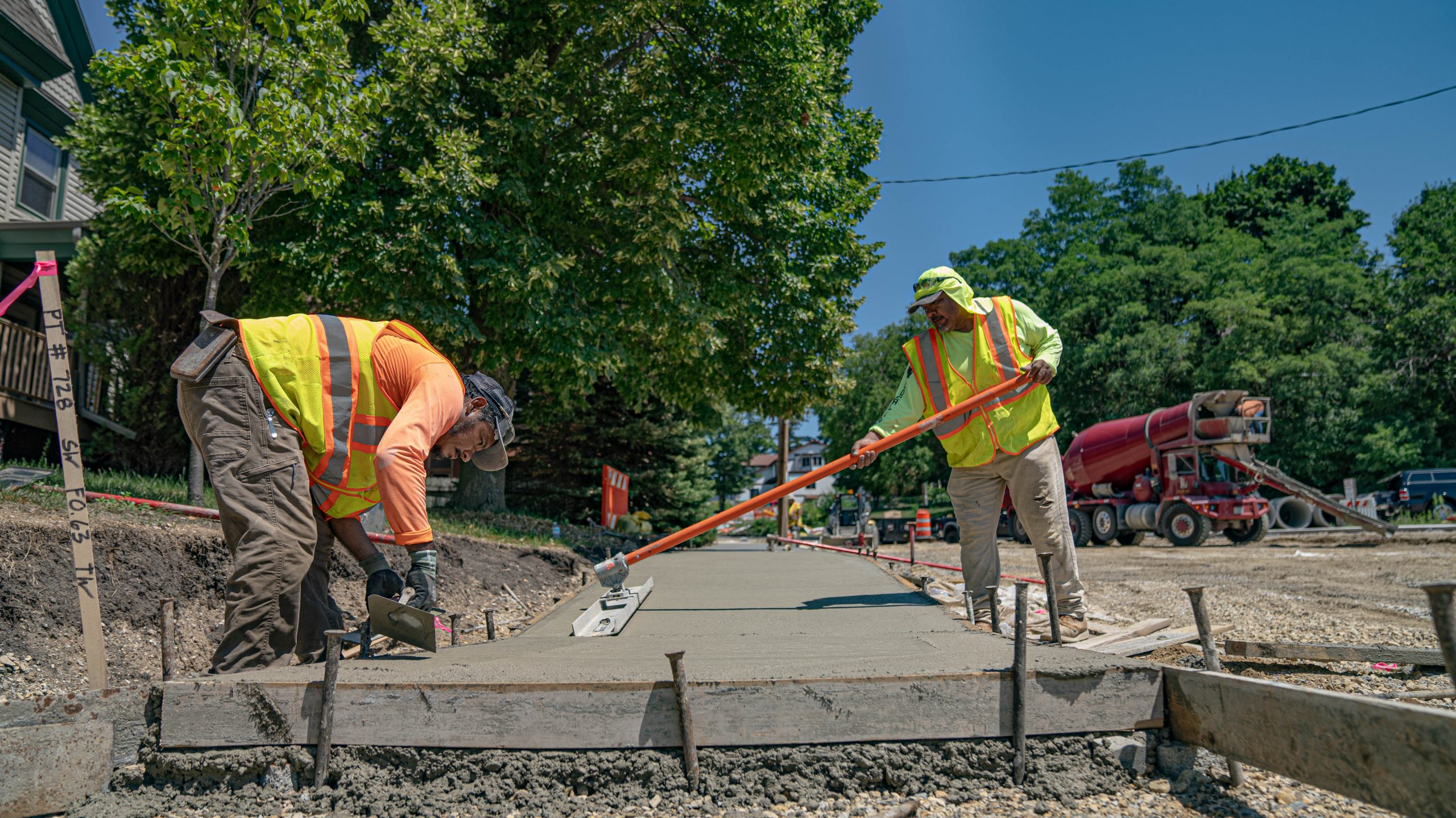 Front view of two workers leveling side walk concrete on East Milwaukee Street