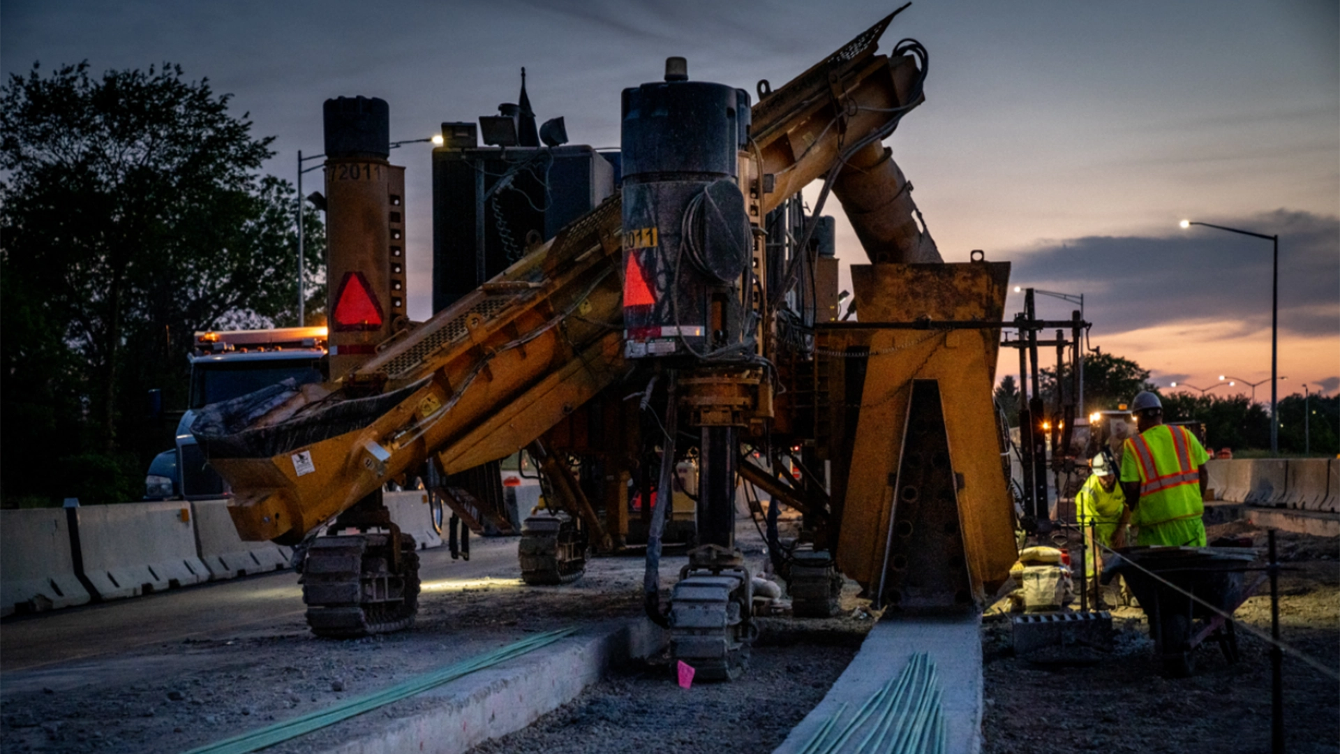 large equipment with construction workers at dawn