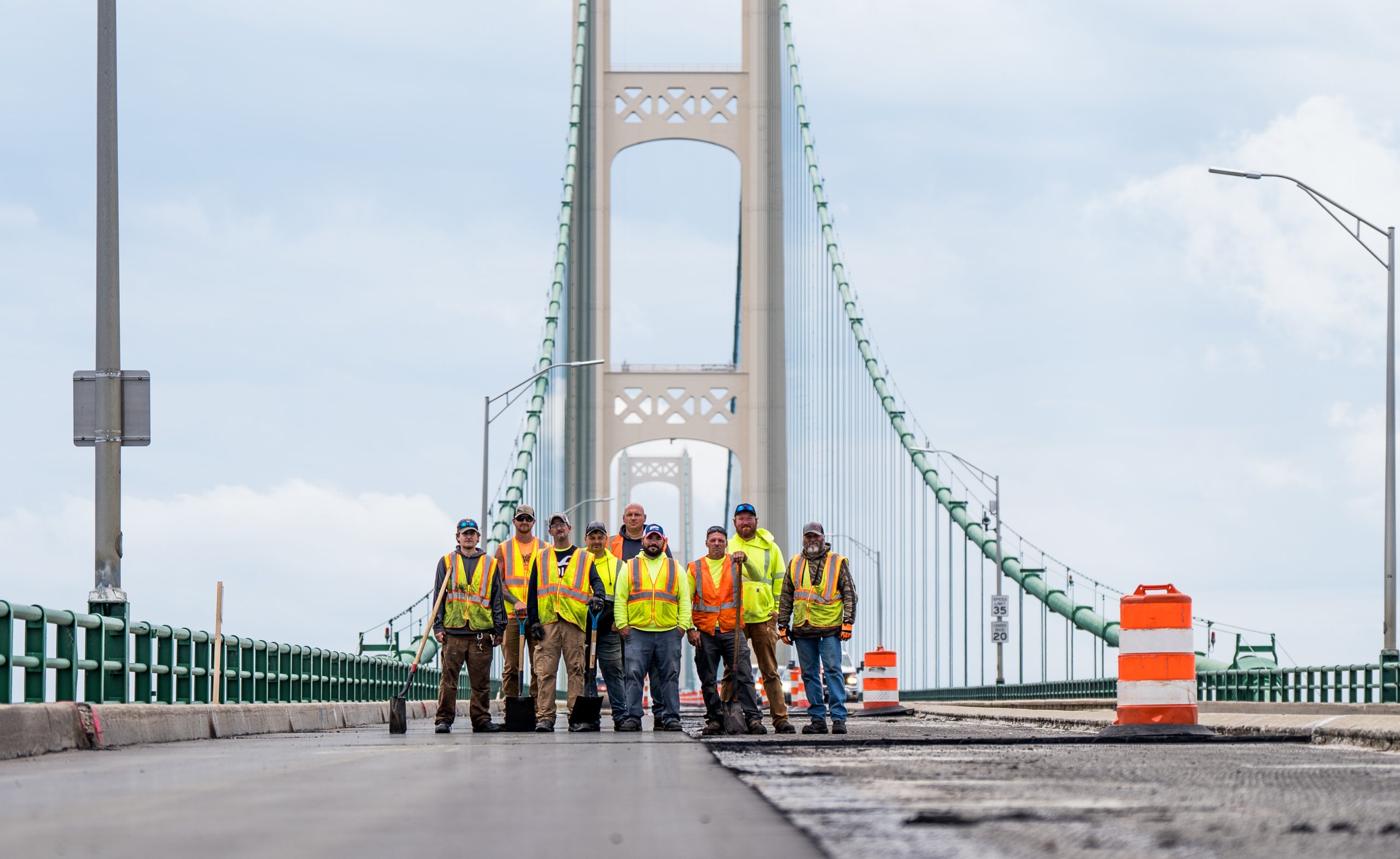 Wide shot of Walbec Group construction team on the Mackinac Bridge, with the bridges tower in the background