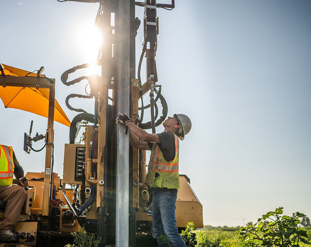 Two construction workers working on installing solar post